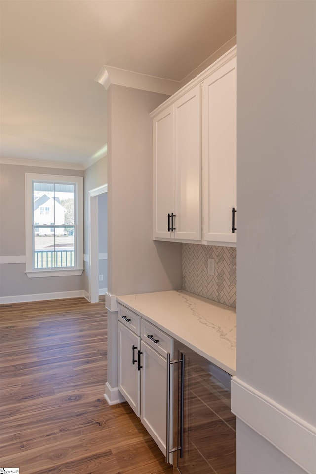 interior space with decorative backsplash, white cabinets, dark wood-type flooring, and light stone counters