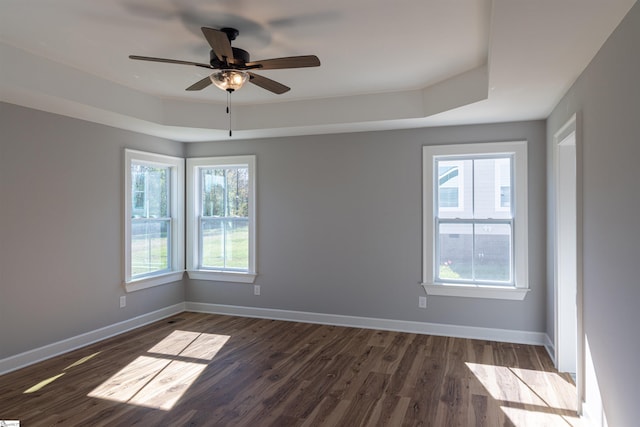 spare room featuring a tray ceiling, ceiling fan, and dark hardwood / wood-style flooring