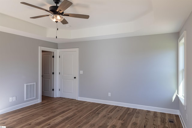 unfurnished room featuring ceiling fan, a raised ceiling, and dark hardwood / wood-style floors