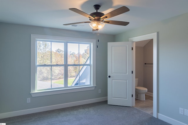 unfurnished bedroom featuring carpet flooring, ensuite bath, and ceiling fan