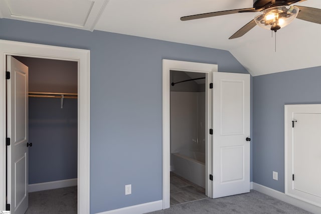 unfurnished bedroom with carpet, vaulted ceiling, a closet, a spacious closet, and ceiling fan