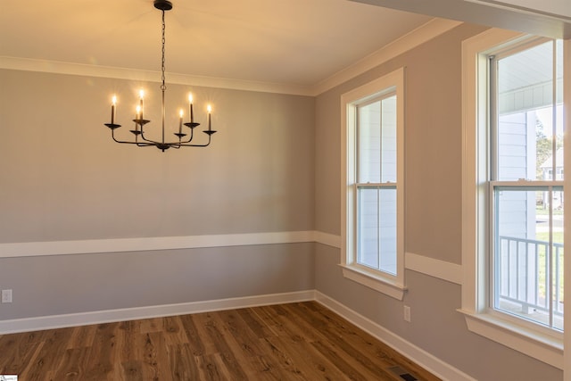 spare room featuring ornamental molding, a notable chandelier, and dark wood-type flooring