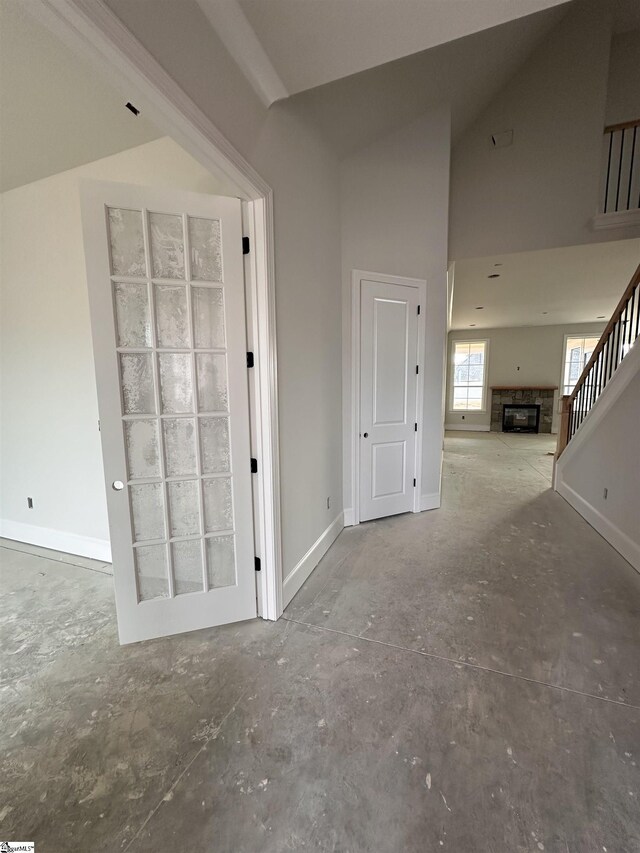 hall featuring high vaulted ceiling and concrete floors