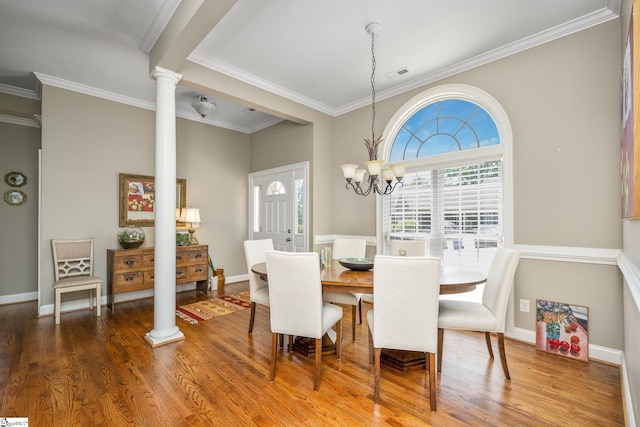 dining room with ornate columns, dark hardwood / wood-style flooring, ornamental molding, and an inviting chandelier