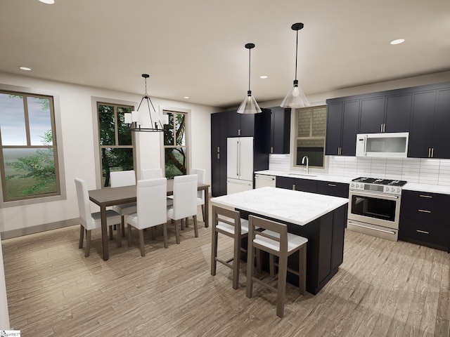 kitchen with pendant lighting, sink, appliances with stainless steel finishes, light hardwood / wood-style floors, and a kitchen island