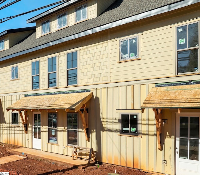 view of front facade featuring board and batten siding and roof with shingles