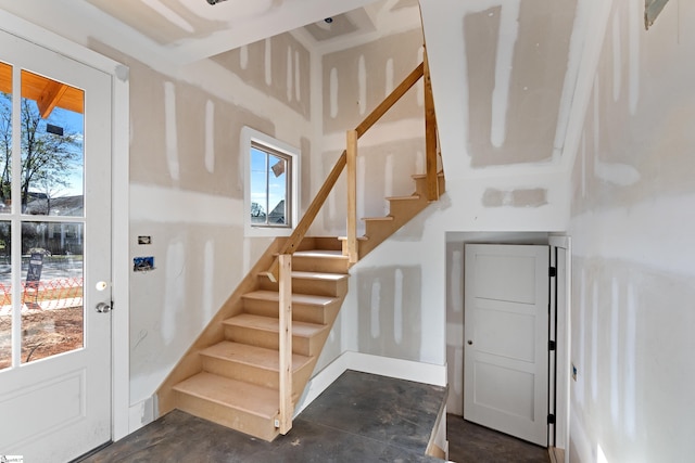 staircase featuring unfinished concrete flooring