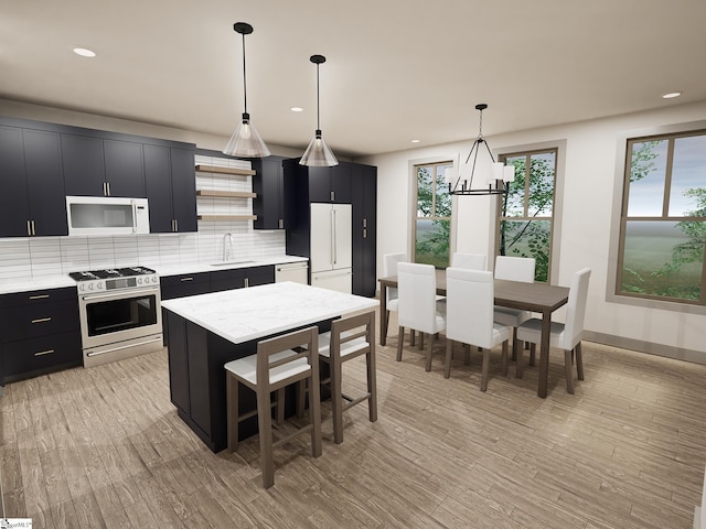 kitchen with white appliances, decorative backsplash, dark cabinetry, light wood-style floors, and a sink