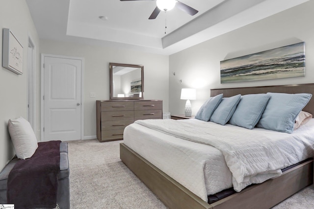 bedroom featuring light colored carpet, ceiling fan, and a tray ceiling