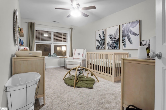 bedroom featuring carpet, ceiling fan, and a nursery area