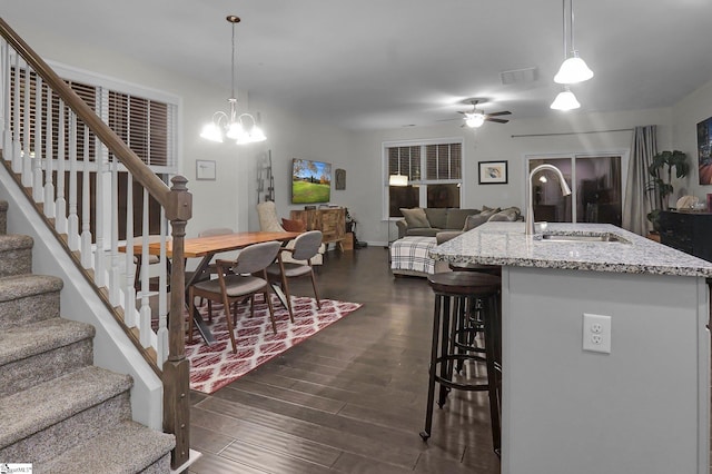 kitchen featuring decorative light fixtures, a kitchen island with sink, dark wood-type flooring, and sink