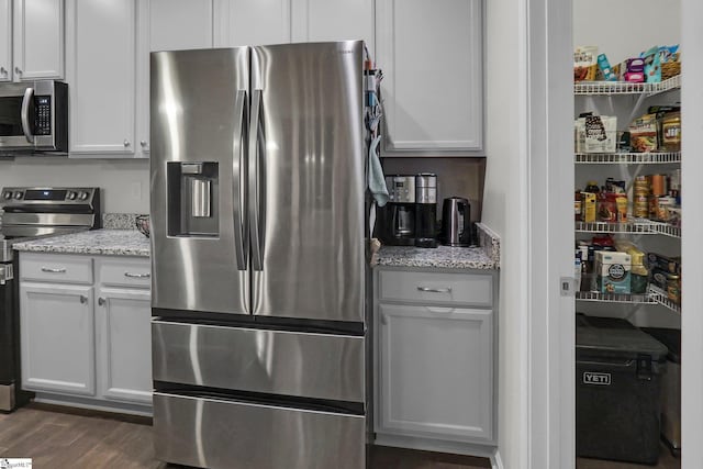 kitchen featuring light stone counters, white cabinetry, stainless steel appliances, and dark hardwood / wood-style floors