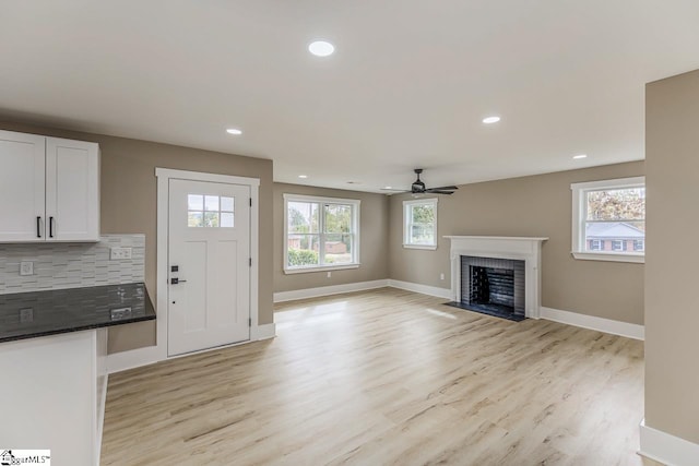 unfurnished living room with light wood-type flooring and ceiling fan