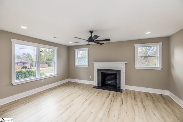 unfurnished living room featuring a fireplace, light hardwood / wood-style flooring, plenty of natural light, and ceiling fan