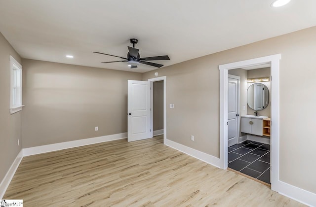 unfurnished bedroom with connected bathroom, light hardwood / wood-style flooring, and ceiling fan