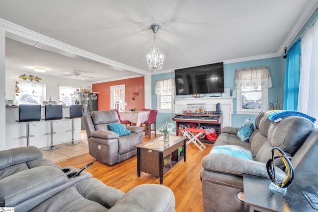 living room featuring hardwood / wood-style floors, ceiling fan with notable chandelier, plenty of natural light, and ornamental molding