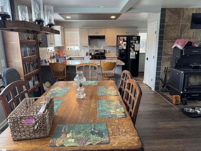 dining room with a wood stove, tile walls, and dark hardwood / wood-style floors