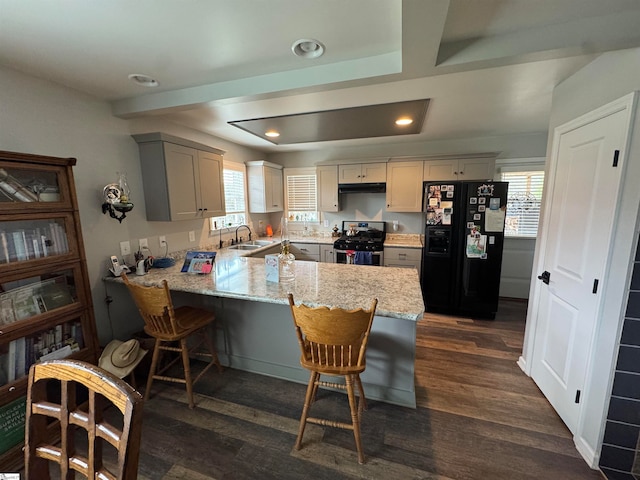 kitchen featuring a healthy amount of sunlight, stainless steel range with gas cooktop, kitchen peninsula, and black refrigerator with ice dispenser