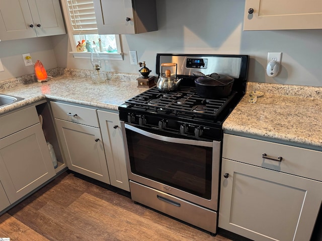 kitchen featuring light stone countertops, dark wood-type flooring, and gas range