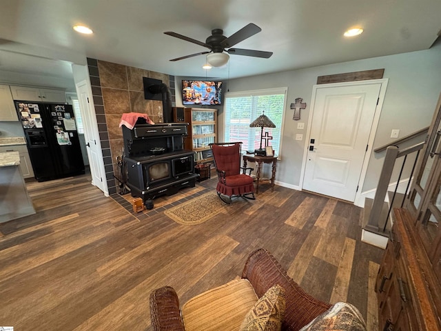 living room featuring a wood stove, ceiling fan, and dark hardwood / wood-style flooring