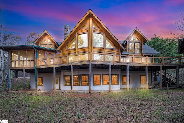 back house at dusk featuring a wooden deck