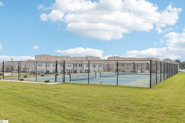 view of tennis court featuring a yard