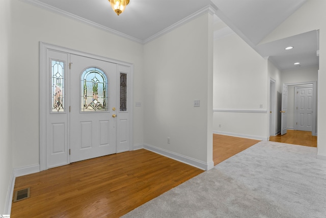 entryway with lofted ceiling, hardwood / wood-style flooring, and ornamental molding