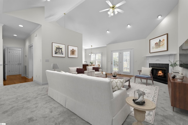 living room featuring ceiling fan, light colored carpet, high vaulted ceiling, and a tiled fireplace