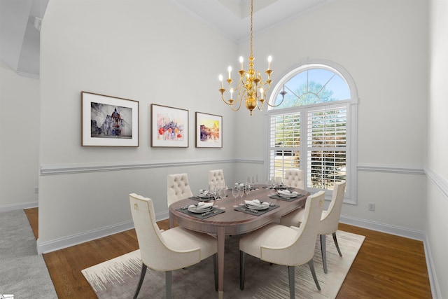 dining room featuring plenty of natural light, a towering ceiling, dark wood-type flooring, and a notable chandelier