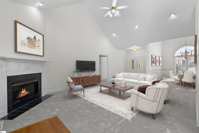 carpeted living room with a fireplace, high vaulted ceiling, and ceiling fan with notable chandelier