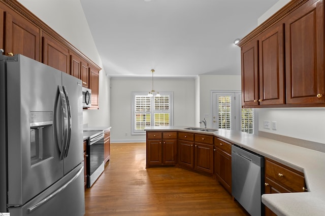 kitchen with hanging light fixtures, stainless steel appliances, a notable chandelier, lofted ceiling, and hardwood / wood-style flooring