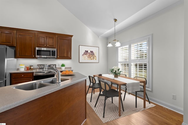 kitchen featuring an inviting chandelier, light hardwood / wood-style flooring, pendant lighting, lofted ceiling, and appliances with stainless steel finishes