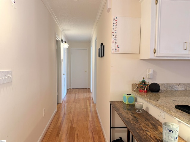 hall with crown molding, light hardwood / wood-style flooring, and a textured ceiling