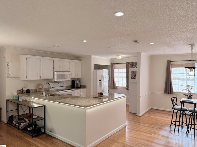 kitchen with white appliances, light hardwood / wood-style floors, white cabinetry, and a wealth of natural light