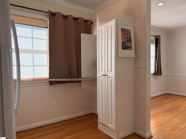 hall with crown molding, plenty of natural light, a textured ceiling, and light hardwood / wood-style flooring