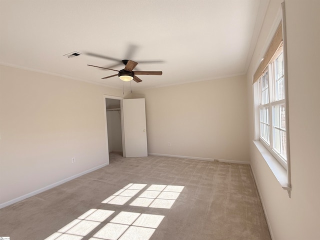 unfurnished bedroom featuring ceiling fan, a closet, light colored carpet, and ornamental molding