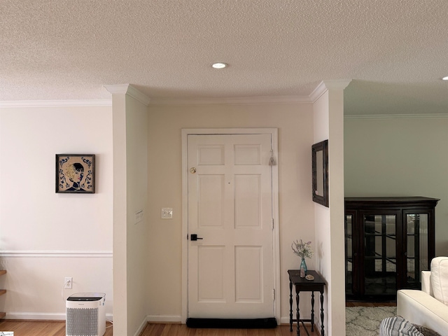 foyer featuring a textured ceiling, wood-type flooring, and ornamental molding