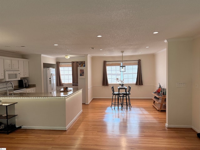 kitchen featuring white cabinets, light wood-type flooring, white appliances, and a wealth of natural light