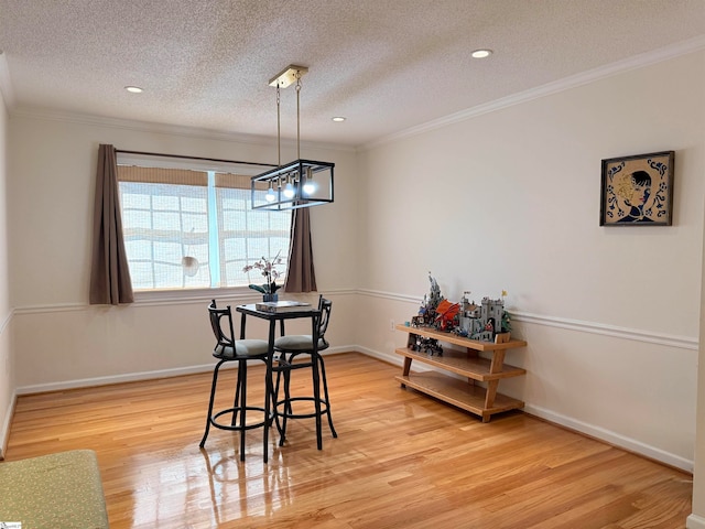 dining room with hardwood / wood-style flooring, ornamental molding, a textured ceiling, and a chandelier