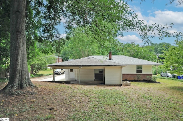 back of house with a lawn and a carport