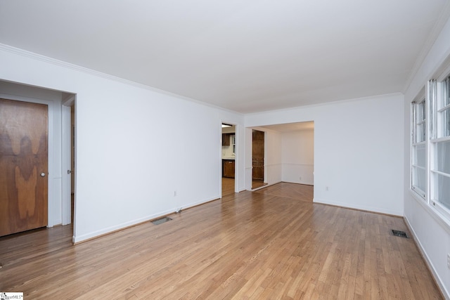 empty room with ornamental molding and light wood-type flooring