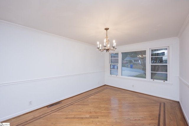 unfurnished dining area with crown molding, an inviting chandelier, and hardwood / wood-style flooring