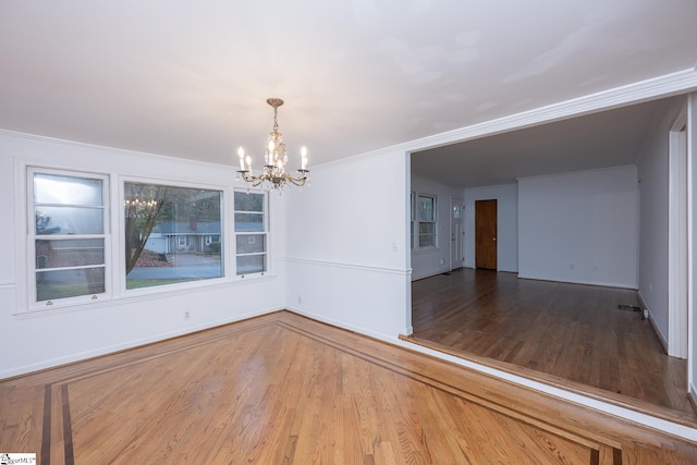 unfurnished dining area featuring hardwood / wood-style flooring, ornamental molding, and an inviting chandelier