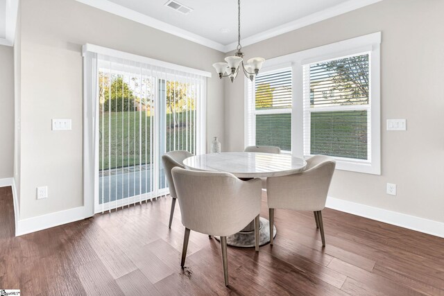 dining room featuring dark hardwood / wood-style flooring, crown molding, and a chandelier