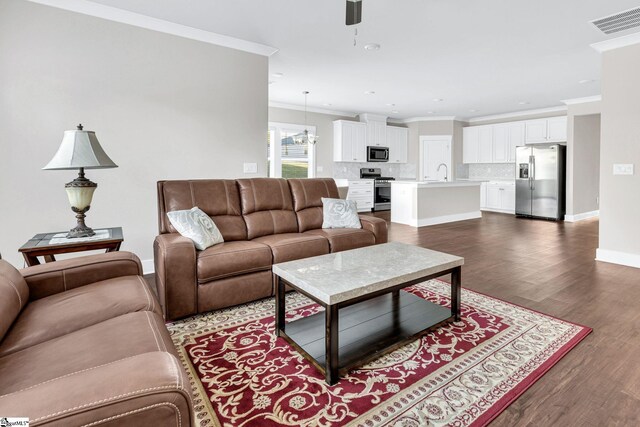 living room with ceiling fan, sink, dark hardwood / wood-style floors, and ornamental molding