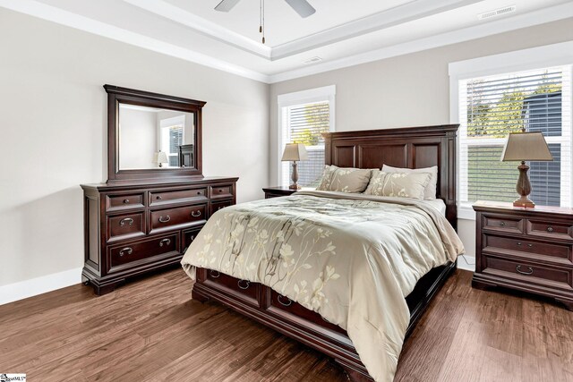 bedroom with a raised ceiling, ceiling fan, crown molding, and dark hardwood / wood-style floors