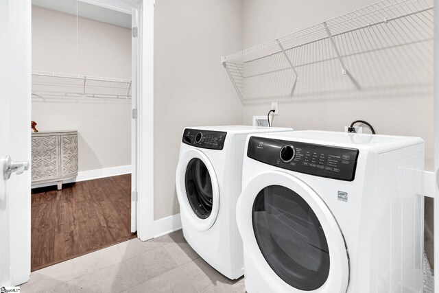 clothes washing area with separate washer and dryer and light wood-type flooring