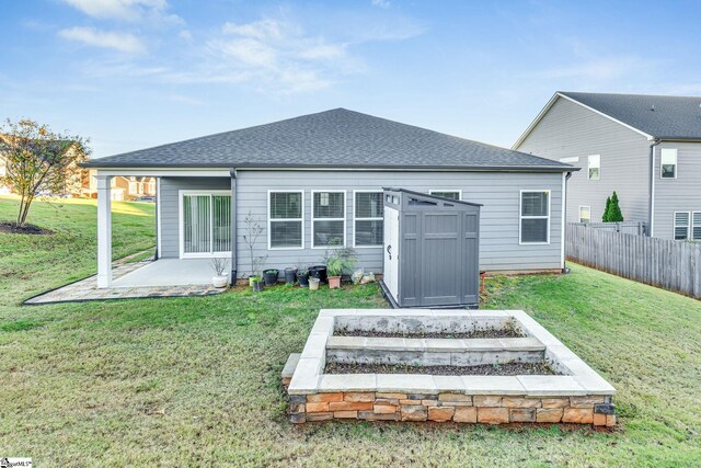 rear view of property with a yard and a storage unit