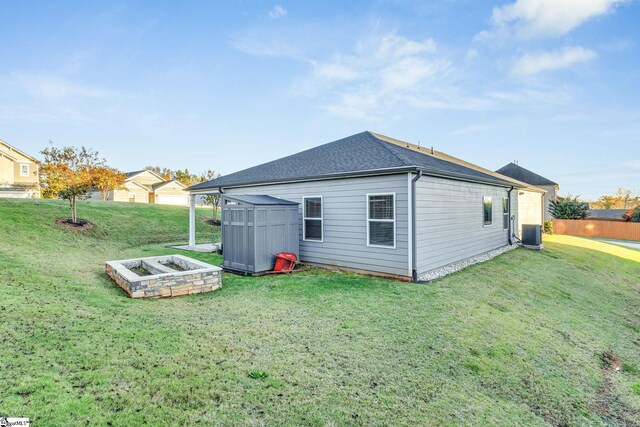 rear view of property featuring central air condition unit and a lawn