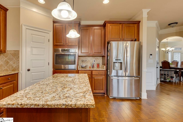 kitchen with a center island, hanging light fixtures, dark wood-type flooring, stainless steel appliances, and decorative backsplash